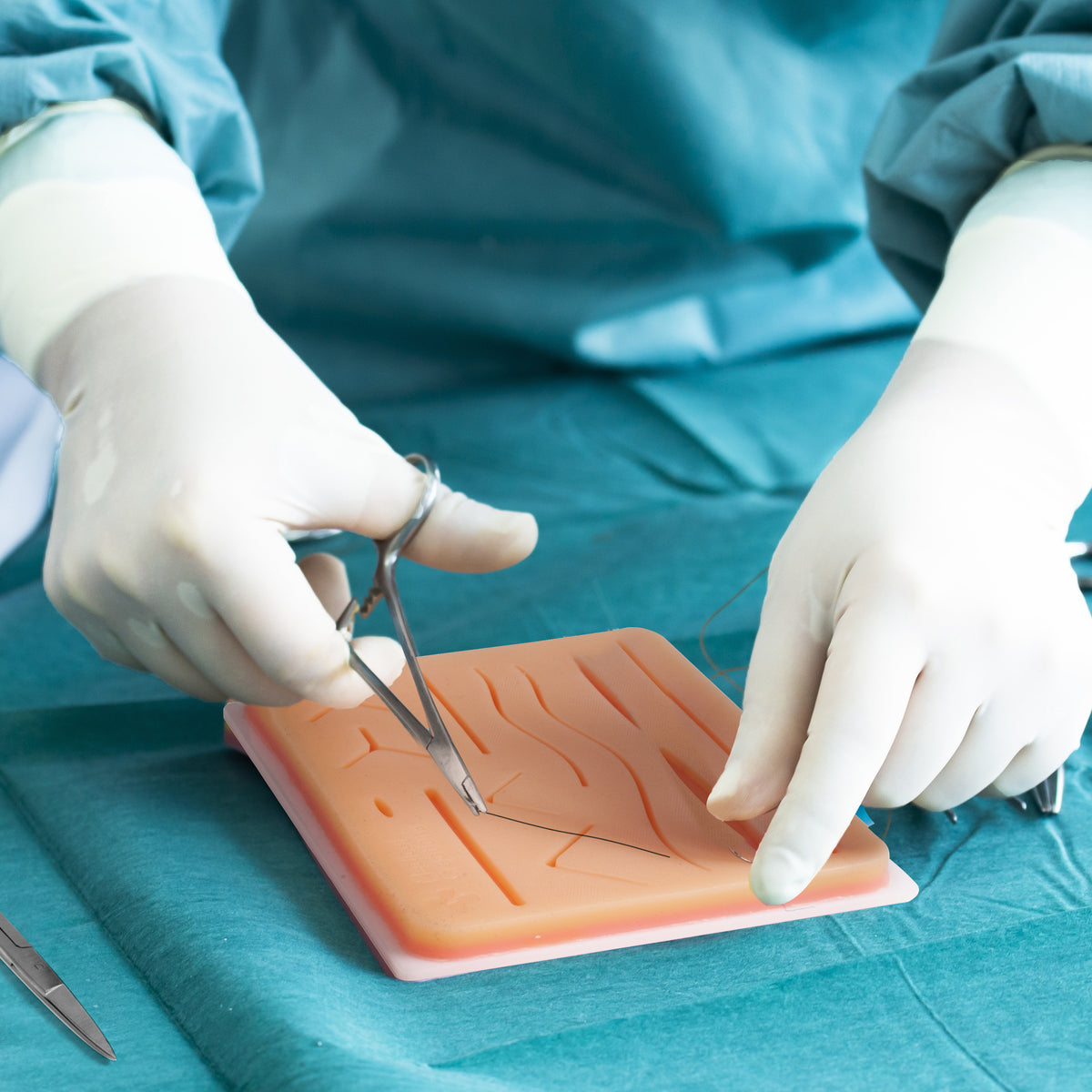 Practicing on the silicone suture practice pad with a needle holder and forceps